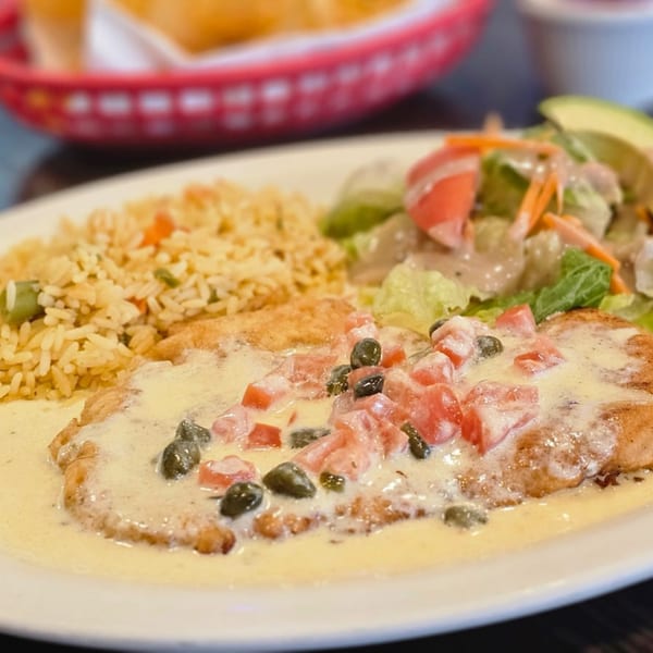 Chicken breast with creamy sauce, diced tomatoes, capers, rice, and a side salad.